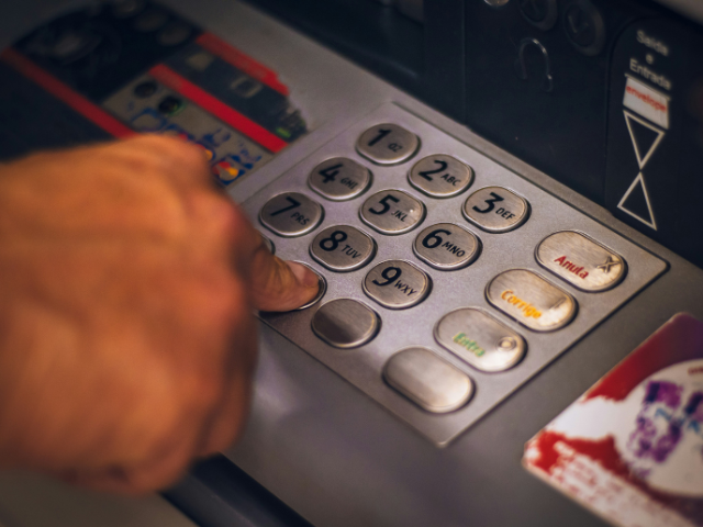 ATMのボタンを操作する手